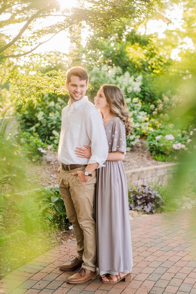 couple looking at each other in front of flowers at their garden engagement session