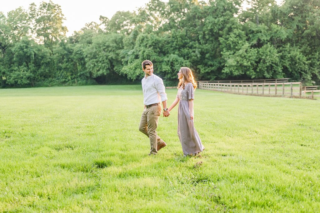couple walking in a field during their engagement photos 