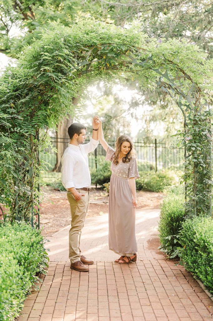 couple dancing under greenery arch in their garden engagement session