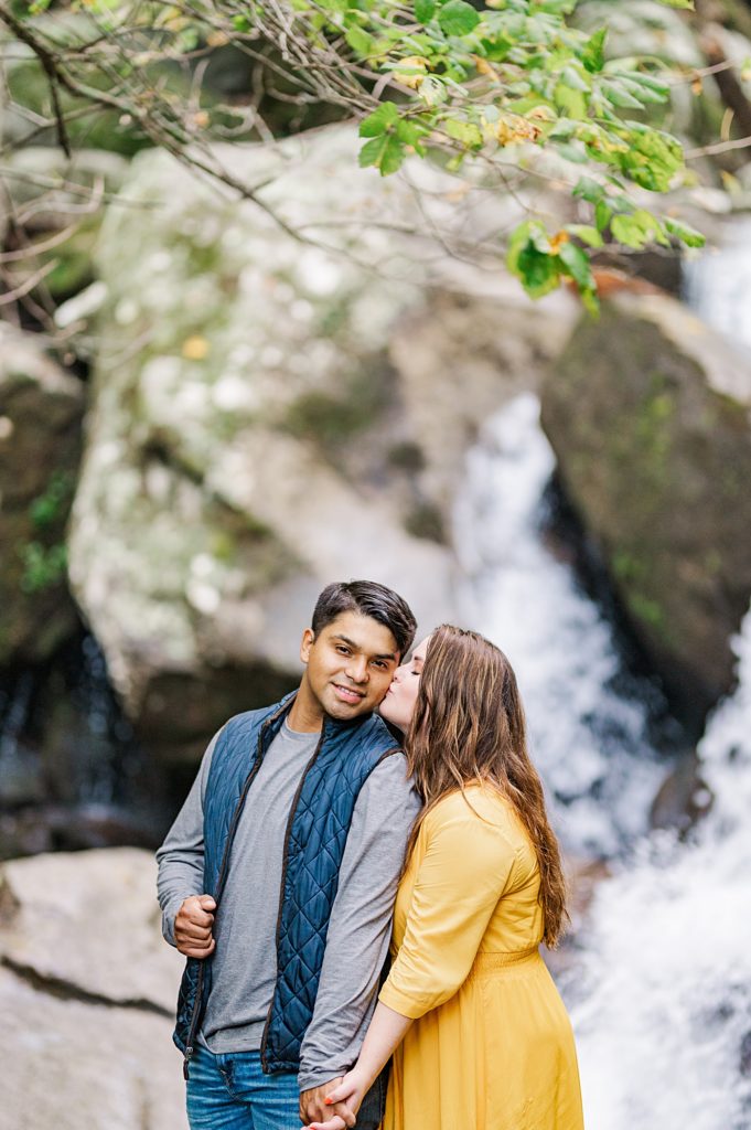 waterfall engagement session with couple standing on a rock