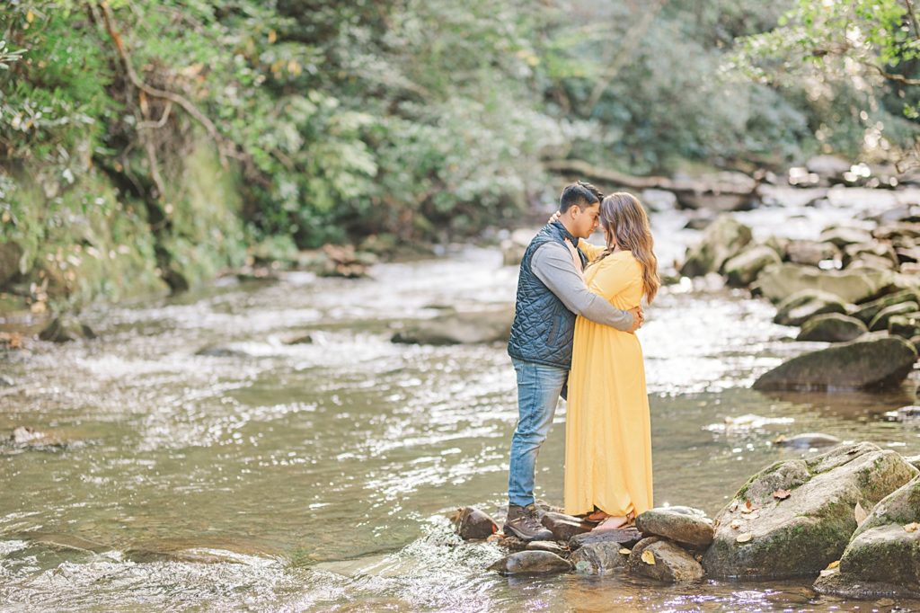 couple standing on rock in a creek during their engagement session