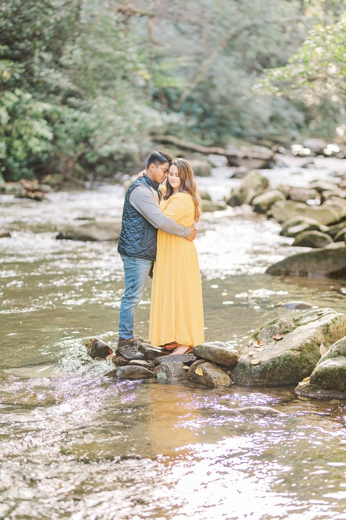 couple standing on a rock in a creek during their engagement session 