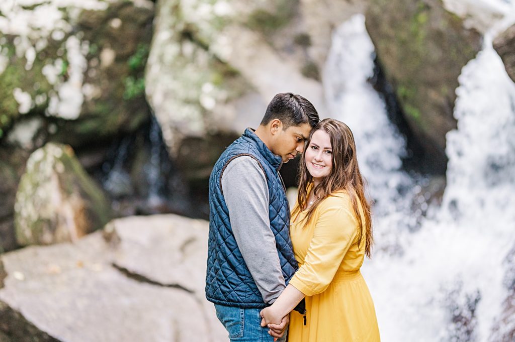 waterfall engagement session with couple standing on a rock