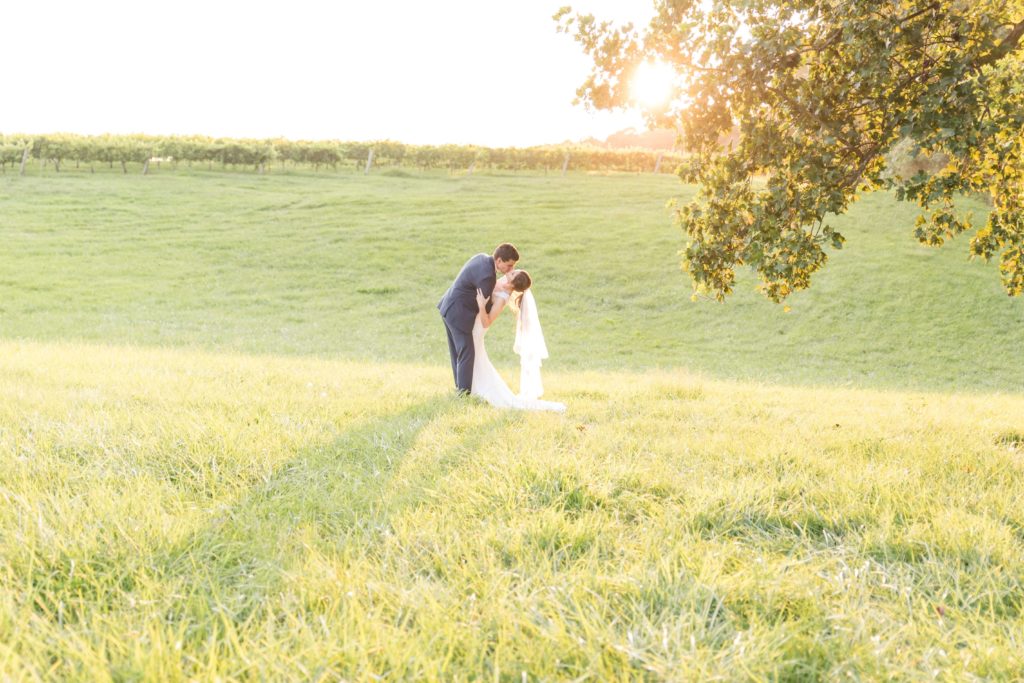 bride and groom in a field kissing