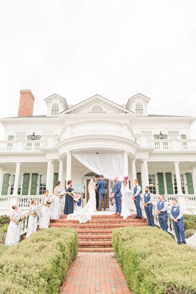 Bridal party standing on Moores spring manor steps during ceremony at a Winston Salem wedding venue