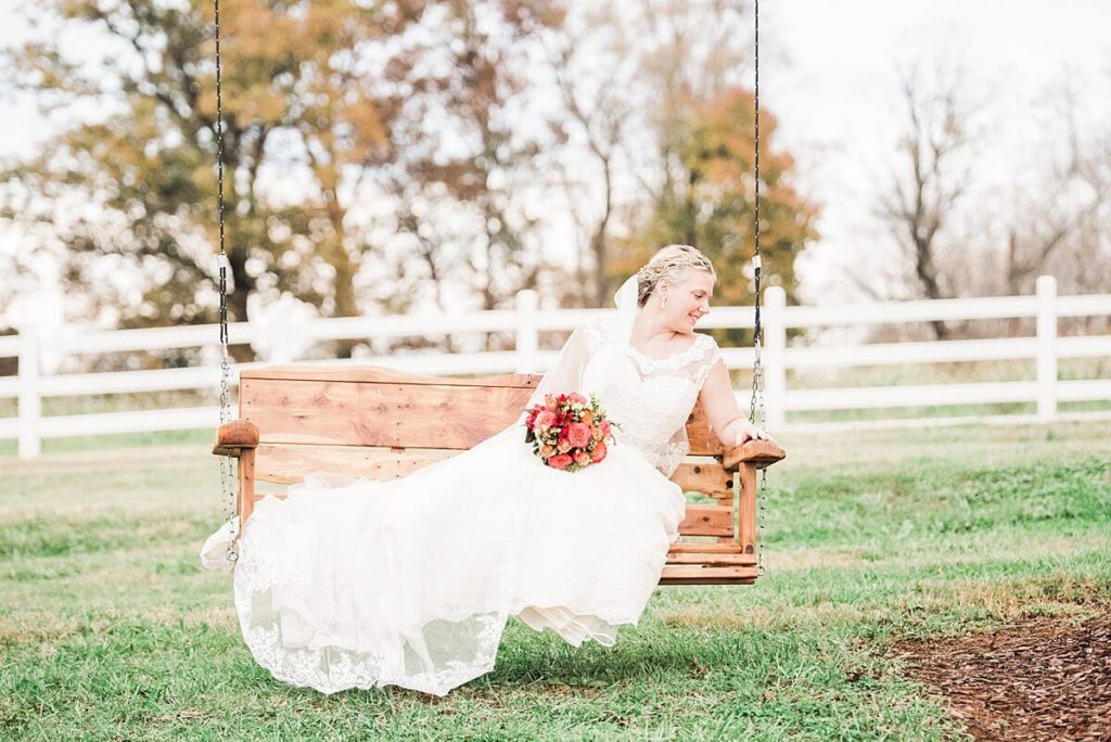 bride sitting on a swing in the field at adaumont farm
